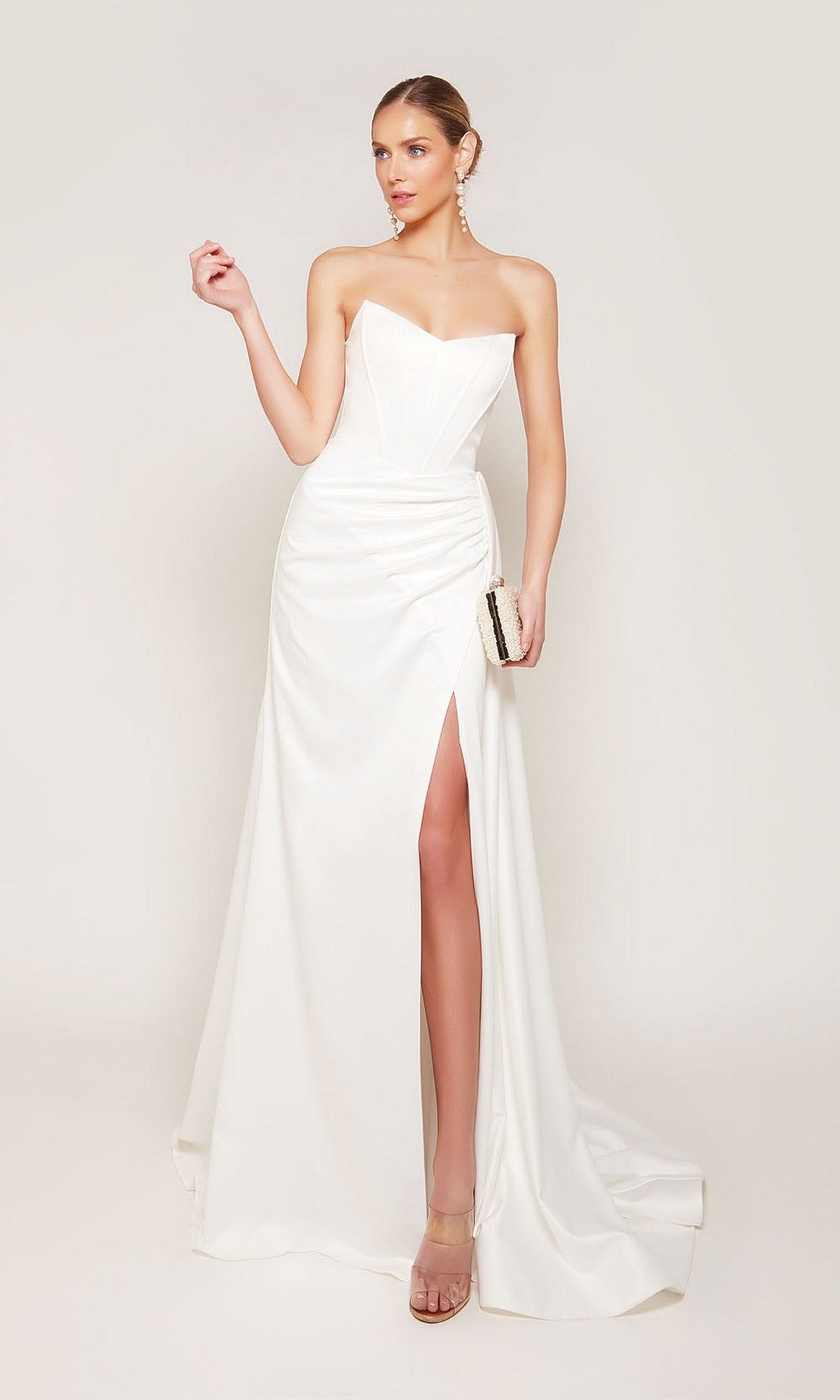 A woman in the Alyce 7093 long formal dress—strapless, satin, with a thigh-high slit—stands against a plain background, holding a small clutch.